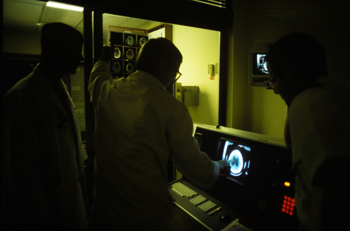 A neurosurgery team gathered around a monitor reviewing brain imaging.
