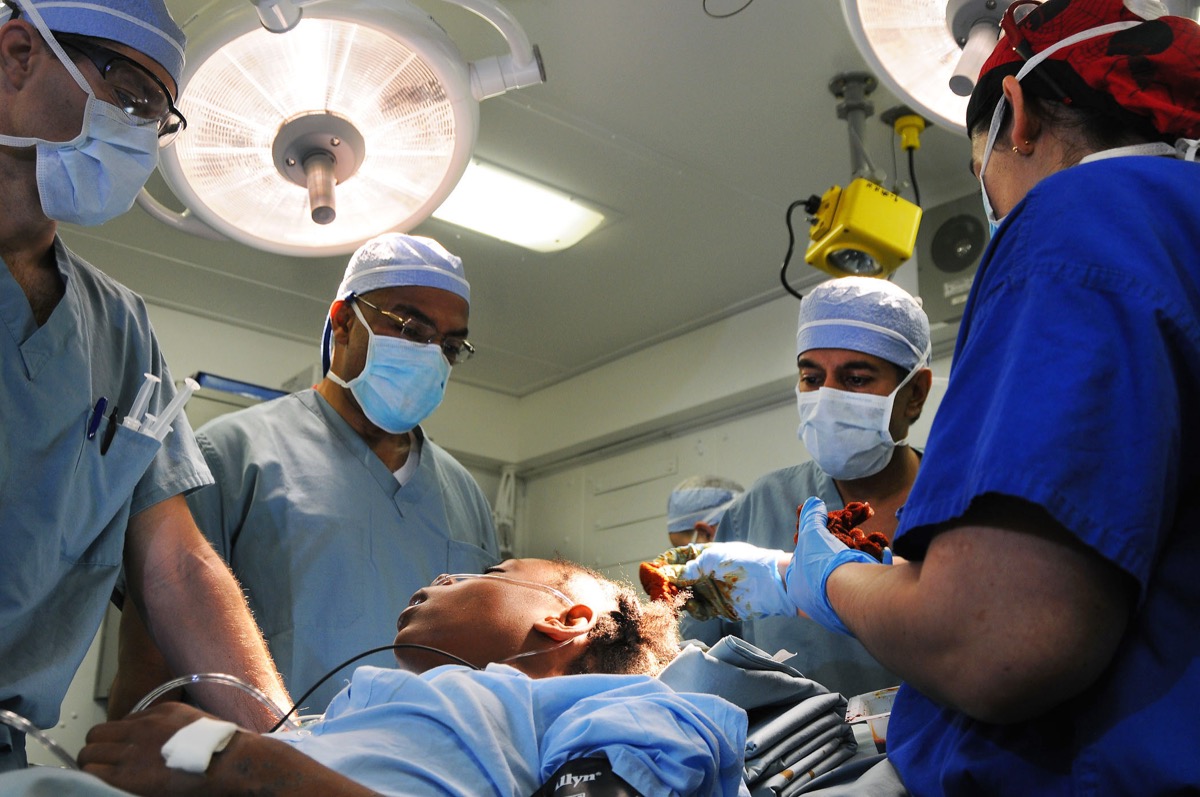 A surgical team in gowns and masks prepares for brain surgery in an operating room.